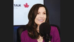 Liberty Talk Canada host speaking into a studio microphone, with the show's maple-leaf logo behind her